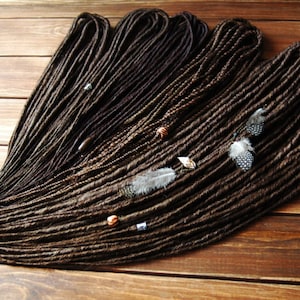 Brown thin dreads with feather beads. Classic dreadlocks