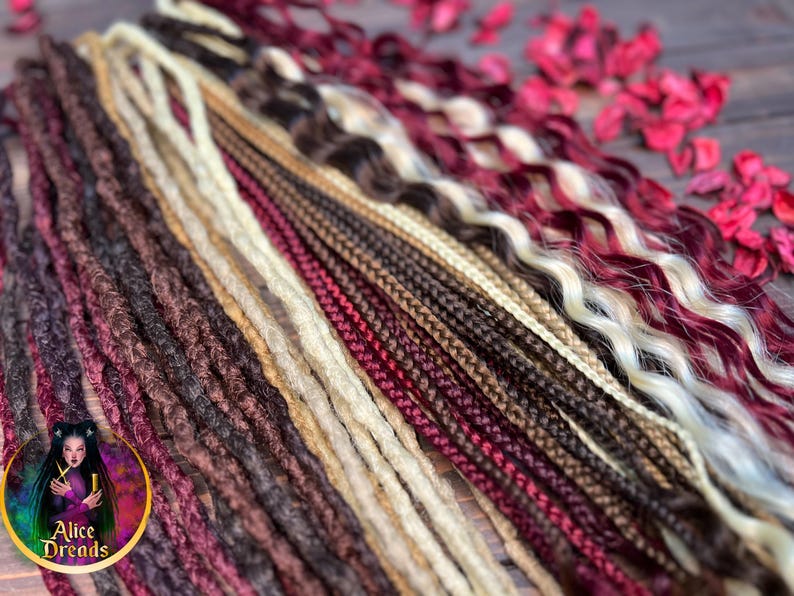May include: A variety of synthetic dreadlocks in different colors and textures, including burgundy, brown, blonde, and black. The dreadlocks are arranged in a fan shape on a wooden surface.