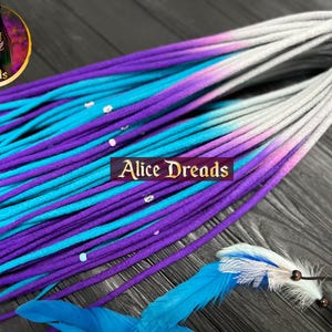 May include: A set of ombre synthetic dreadlocks in shades of purple, teal, and white. The dreadlocks are arranged in a fan shape and have a subtle sheen.