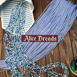 May include: A set of light blue synthetic hair extensions featuring a mix of solid light blue strands and strands adorned with small white, dark blue, and turquoise beads. The text Alice Dreads is displayed in the centre of the image.