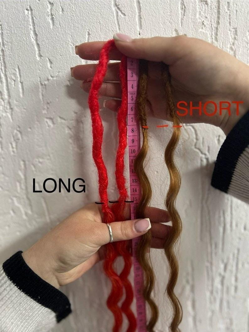 May include: Two sets of synthetic dreadlocks, one red and one brown, are shown next to a measuring tape. The red dreadlocks are 15 inches long and the brown dreadlocks are 8 inches long. The text "LONG" is written next to the red dreadlocks and the text "SHORT" is written next to the brown dreadlocks.