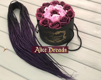 May include: A bundle of dark purple synthetic dreadlocks with a box of pink and burgundy roses in the background. The box has a black lid with the words "Forever Love You" in gold lettering.
