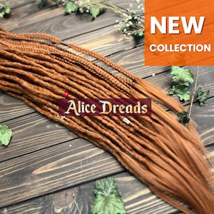 May include: A bundle of auburn-colored dreadlocks, with a few braided strands, arranged on a wooden surface. The image includes the text "Alice Dreads" and "NEW COLLECTION" in an orange box.