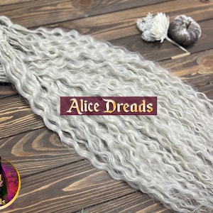 May include: A bundle of wavy, light gray dreadlocks, with the text "Alice Dreads" on a maroon banner. The dreadlocks are arranged on a wooden surface, with decorative flowers and a logo in the corner.