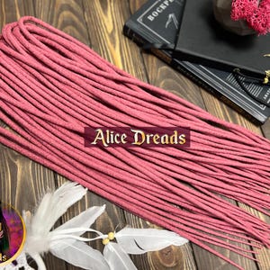 May include: A bundle of pink synthetic dreadlocks, approximately 20 inches long. The dreadlocks are made of a soft, textured material and are ready to be installed.