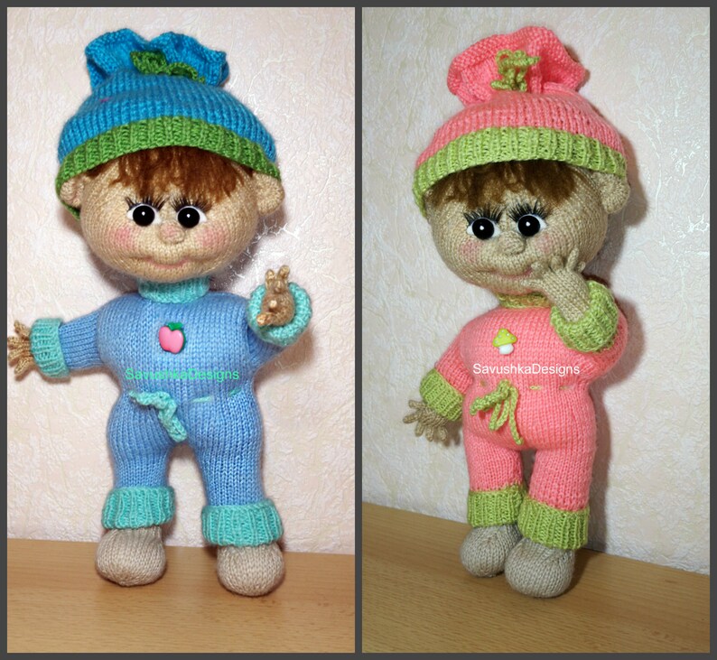 A knitted baby doll wearing a blue jumpsuit and a hat, sitting in a woven basket with a pillow. The doll is handmade, with a cute face, black eyes, and an adorable expression. The PDF pattern is available for download and includes detailed instructions.