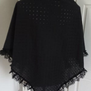 May include: Black lace shawl with a dotted pattern. The shawl is displayed on a mannequin.