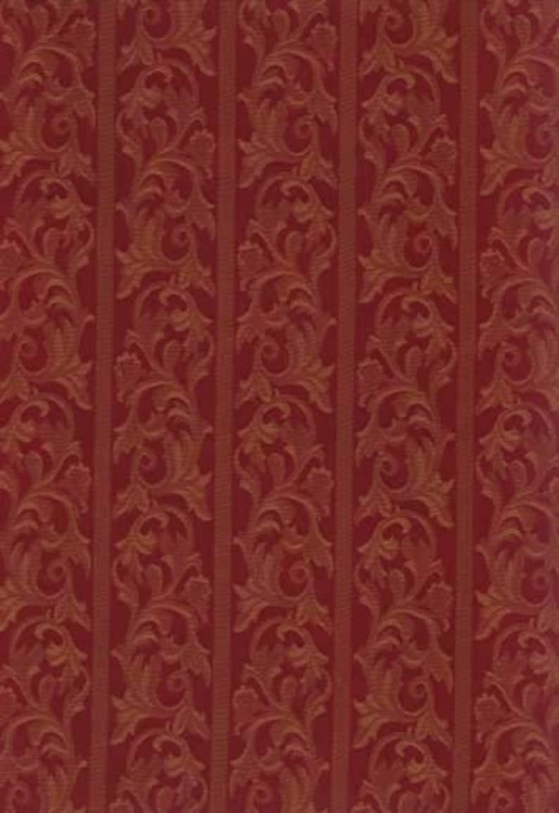 May include: Red and gold patterned fabric with a vertical stripe design. The pattern features ornate, swirling floral and leaf motifs. The fabric has a textured appearance, suitable for upholstery or decorative projects.