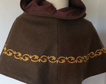 May include: A brown hooded cape with a gold and white embroidered trim. The cape is lined with a brown fabric.