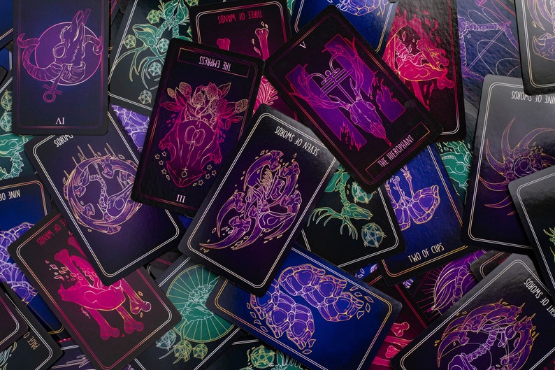 May include: A collection of tarot cards with dark backgrounds and neon illustrations. The cards feature various symbols and text, including "The Empress," "Seven of Swords," and "Two of Cups." The color palette includes purple, pink, blue, and green.