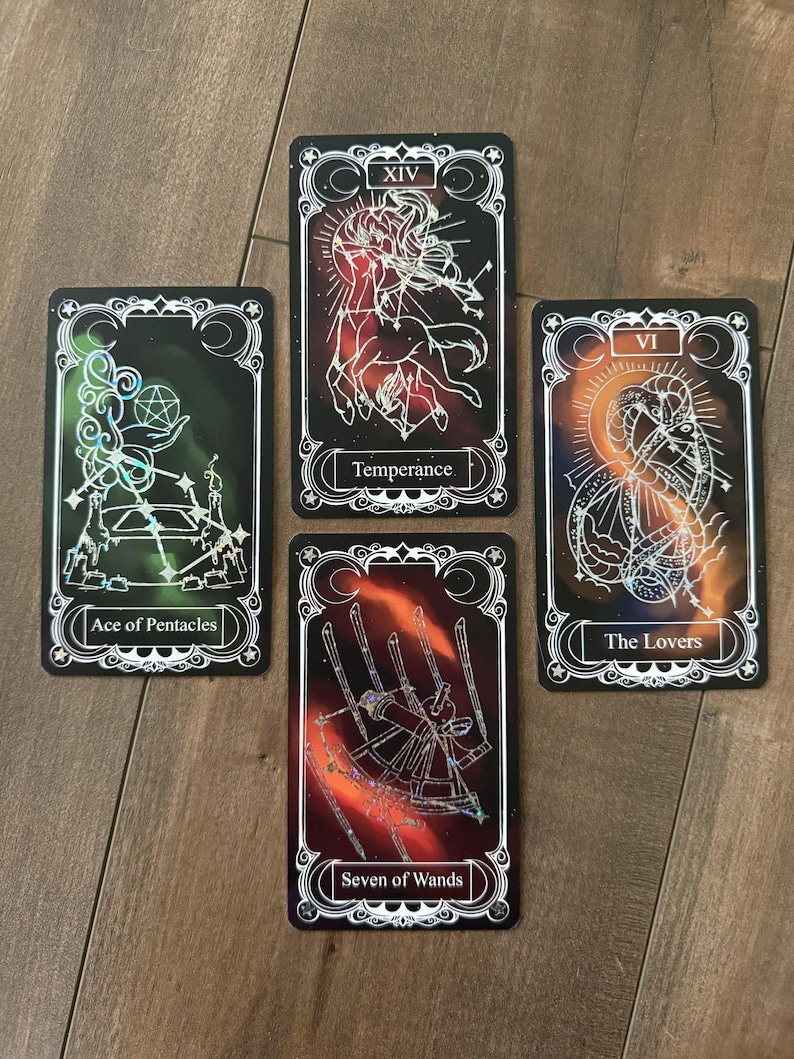 May include: Four rectangular tarot cards with black backgrounds and white line art. The cards are labeled Ace of Pentacles, Temperance, The Lovers, and Seven of Wands. Each card features a unique celestial or symbolic illustration with holographic accents.