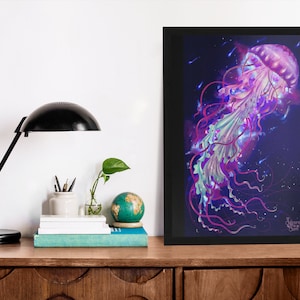 May include: A framed art print featuring a vibrant jellyfish illustration. The artwork showcases a jellyfish with a pink, purple, and teal color palette against a dark blue background. The print is displayed on a wooden surface, alongside a black desk lamp, books, and a globe.