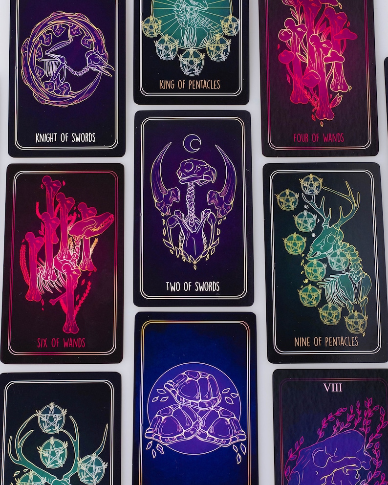 May include: A collection of tarot cards with dark backgrounds and gold and neon illustrations. The cards feature images of skeletons, mushrooms, and other mystical symbols. Text on the cards includes "Knight of Swords", "King of Pentacles", and "Two of Swords".