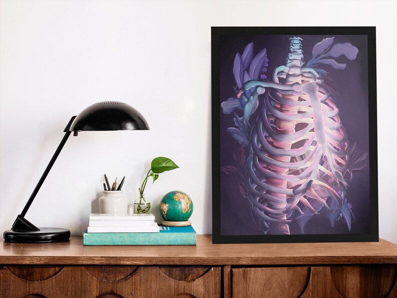 May include: A framed print of a skeletal ribcage with purple and pink flowers growing through it. The background is a dark purple.