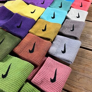 Pode incluir: Uma pilha de meias coloridas com um logotipo Nike swoosh. As meias est&atilde;o dispostas em um padr&atilde;o de arco-&iacute;ris, com cada meia de uma cor diferente.