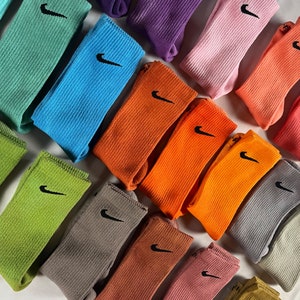 Pode incluir: Uma cole&ccedil;&atilde;o de meias coloridas com um logotipo da Nike. As meias est&atilde;o dispostas em uma variedade de cores, incluindo verde, azul, laranja, rosa e cinza.