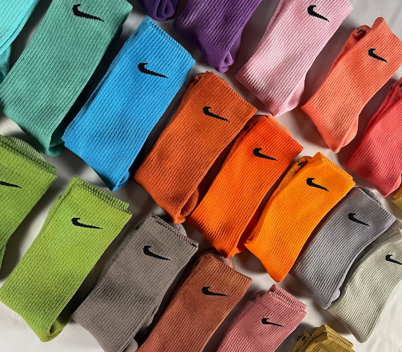 Pode incluir: Uma cole&ccedil;&atilde;o de meias coloridas com um logotipo da Nike. As meias est&atilde;o dispostas em uma variedade de cores, incluindo verde, azul, laranja, rosa e cinza.