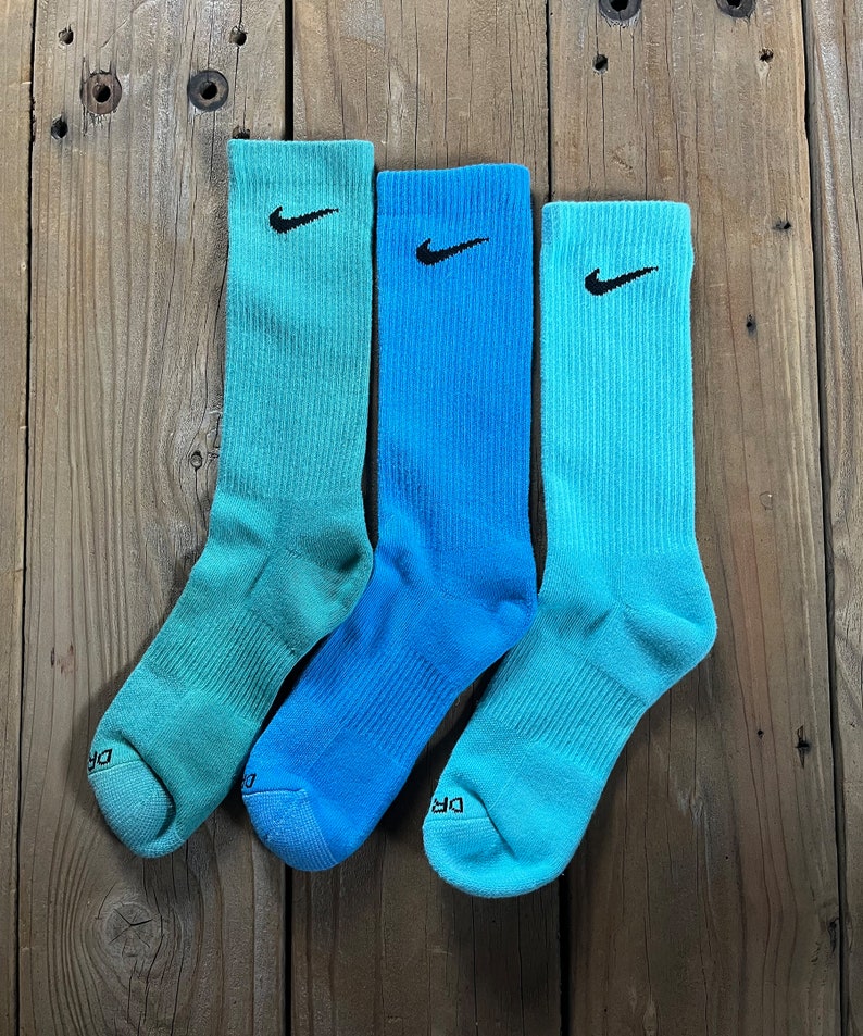 Pode incluir: Tr&ecirc;s pares de meias em diferentes tons de azul e verde. Cada meia tem um logotipo Nike swoosh preto.
