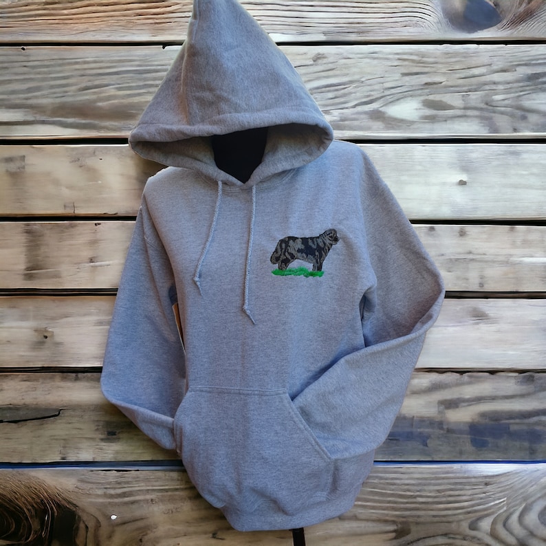 May include: A gray hooded sweatshirt with a black and white embroidered dog on the front. The dog is standing on a green patch of grass.