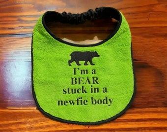 May include: Green baby bib with black trim and a black embroidered bear with the text "I'm a BEAR stuck in a newfie body".