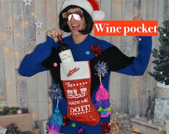 May include: A blue Christmas sweater with a wine pocket, a red stocking that says "The Elf Made Me Do It!", and colorful tassels. The person is wearing a Santa hat and sunglasses, holding a bottle of wine.