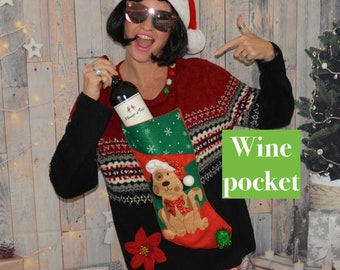 May include: A red and black Christmas sweater with a wine bottle holder shaped like a stocking with a dog on it. The stocking is green and red with snowflakes and a white pom-pom. The sweater has a red and white pattern and the text "Wine pocket" is written on a green background.