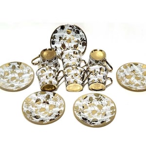 May include: A vintage tea set featuring six cups, saucers, and a serving plate. The white porcelain is decorated with gold leaf patterns and gold trim. The cups have gold-colored interiors and handles.