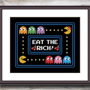 Peut inclure: Un motif de point de croix représentant des personnages de Pac-Man dans un labyrinthe bleu avec le texte "Eat the Rich!" en rouge et blanc.
