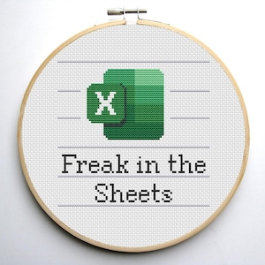 May include: A cross-stitch embroidery hoop featuring the Microsoft Excel logo in green and white, with the text "Freak in the Sheets" stitched below. The embroidery is set in a round wooden hoop.