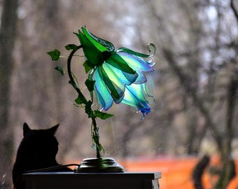 湾曲した真鍮の脚に取り付けられた緑と青の花形のテーブルランプ