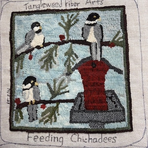 May include: A handmade fiber art piece titled "Tangleweed Fiber Arts" featuring three chickadees perched on branches with red berries. The birds are depicted in gray, black, and white, set against a light blue background. The text "Feeding Chickadees" is at the bottom.