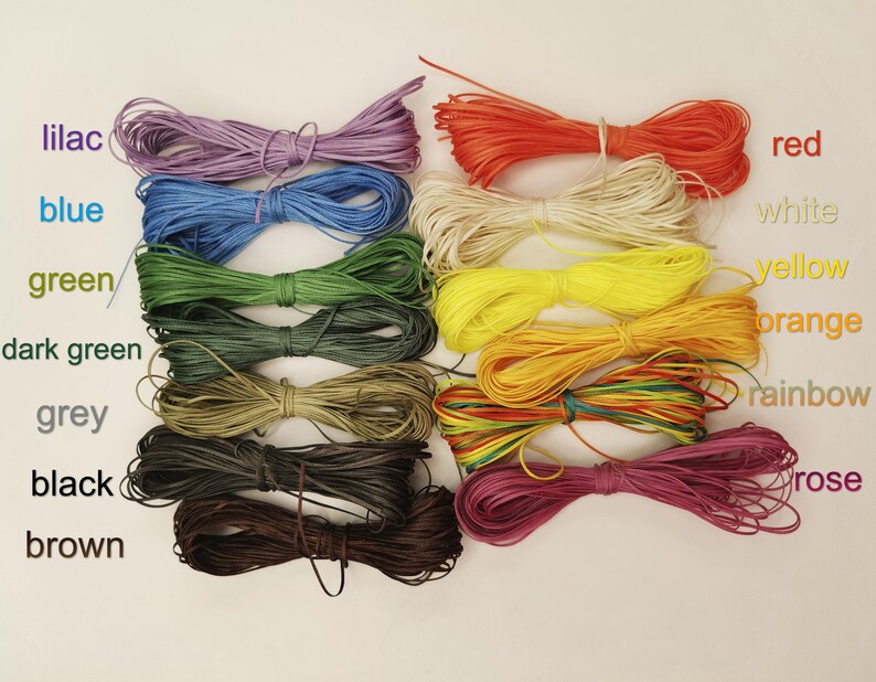 K&ouml;nnte beinhalten: Sortiment von 12 Spulen gewachster Baumwollschnur in verschiedenen Farben, darunter Lila, Blau, Gr&uuml;n, Dunkelgr&uuml;n, Grau, Schwarz, Braun, Rot, Wei&szlig;, Gelb, Orange und Regenbogen.