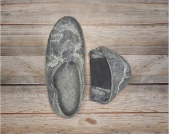 May include: A pair of grey wool slippers with a decorative pattern. One slipper is shown with the sole facing up, while the other slipper is shown with the top facing up.