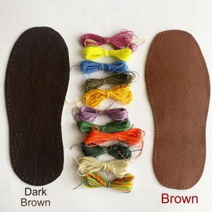 K&ouml;nnte beinhalten: Zwei Ledersohlen zum Schuhmachen, eine dunkelbraun und eine braun, mit einer Vielzahl von farbigen F&auml;den zum N&auml;hen.