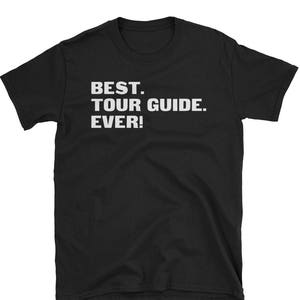 Peut inclure: T-shirt noir avec du texte blanc qui dit "BEST. TOUR GUIDE. EVER!"