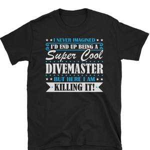 May include: Black t-shirt with white text that reads "I never imagined I'd end up being a Super Cool Divemaster. But here I am killing it!"