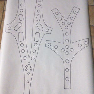 May include: Three black line drawings of abstract shapes on a white background. The shapes include two similar asymmetrical designs with circles and rectangles, and a third Y-shaped design with circles.