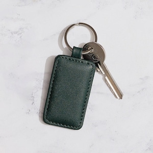 May include: A dark green leather keychain with a silver key ring and two keys.