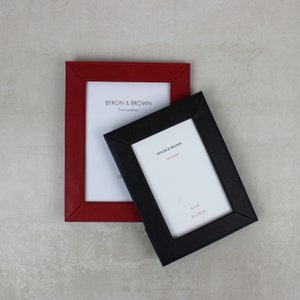 May include: Two leather picture frames, one red and one black, with the text "BYRON & BROWN Fine Leather" on each. The black frame is 6" x 4" (15 x 10 cm).