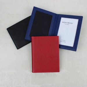 Könnte beinhalten: Drei Leder-Bilderrahmenhalter in Rot, Schwarz und Blau. Der blaue Rahmen trägt den Text "BYRON & BROWN Fine Leather 5" x 3 3/4" 12.5 x 9 cm" auf der Innenseite.