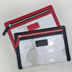 May include: Two rectangular pouches with clear plastic centers and textured borders. One pouch features a red border with a matching red tab, while the other has a black border with a matching black tab. Both include silver metal zippers.