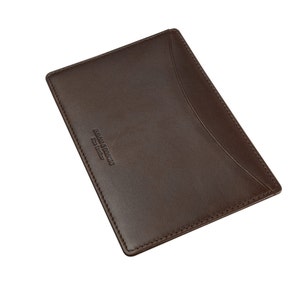 Puede incluir: Un porta tarjetas de cuero marr&oacute;n con el texto "DR. MARTENS" y "Fine Leather" grabado en la parte delantera.