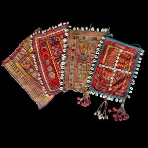 Puede incluir: Cinco bolsas de tela bordadas de colores con adornos de conchas. Las bolsas están decoradas con patrones geométricos y piezas de espejo.