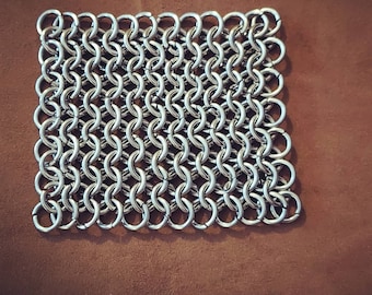 May include: A silver chainmail square, made of interlocking metal rings. Chainmail is a type of woven metal mesh that has been used for centuries as armour.