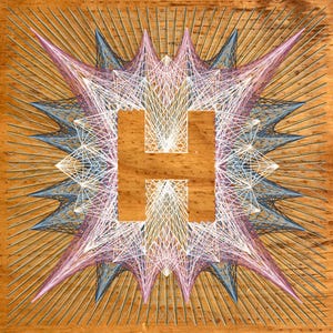 以下が含まれることがあります： 木製の芸術作品で、中央に「H」の文字がストリングアート技法で描かれています。 白、ピンク、青の糸が文字から放射状に広がるデザインです。 背景は暖かく明るい茶色の木材です。
