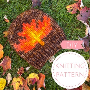 May include: DIY knitting pattern for a brown knit hat with an orange, yellow, and red leaf design. The hat is lying on a bed of green grass and fall leaves.