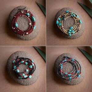 May include: Four different beaded necklaces with turquoise and other coloured beads, displayed on grey stones.