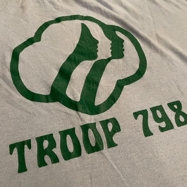 Może przedstawiać: Szary T-shirt z zielonym logo Girl Scout i nadrukiem "TROOP 798" z przodu.