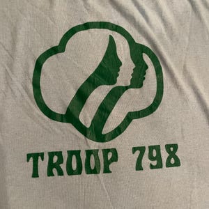 Może przedstawiać: Jasnoszary t-shirt z zielonym logo Girl Scout i nadrukiem "TROOP 798" z przodu.