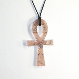 May include: A pink and silver Ankh pendant necklace with a black cord.